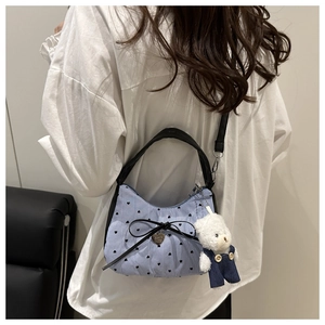 Detail of blue striped crossbody bag with black heart embroidery and cute bear charm