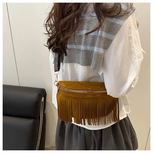 Close-up of brown suede tassel belt bag with ethnic patterned strap and metal hardware