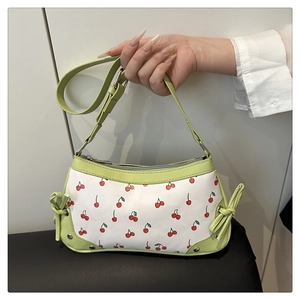 Detail of light green bow accents and cherry pattern on a women's leather shoulder bag