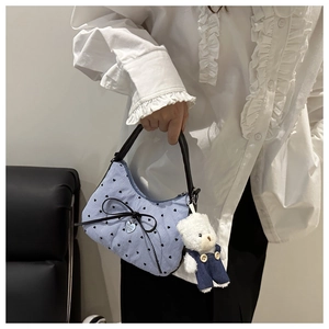 Detail of blue striped tote bag with black leather bow and cute teddy bear charm
