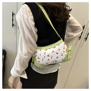 Detail of green and white cherry print shoulder bag with bow and silver rivets