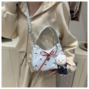 Light blue half-moon crossbody bag with red bow pattern and white teddy bear plush charm