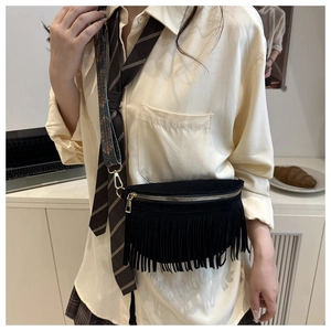 Detail of black suede crossbody bag featuring long fringe and colorful woven shoulder strap