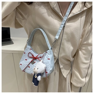 Detail of light blue crossbody crescent bag with red bows and plush bear charm