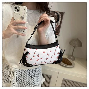 Mirror selfie showing a cherry print shoulder bag with black bow and rivet details