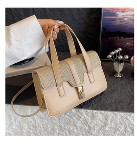 Detail of beige handbag with gold sequin flap and metallic clasp on a leather texture