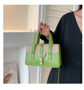 Detail of green leather and woven fabric shoulder bag with golden twist lock hardware