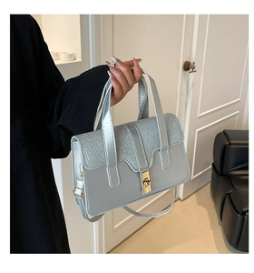 Detail of light blue textured handbag with golden twist lock and wave pattern finish