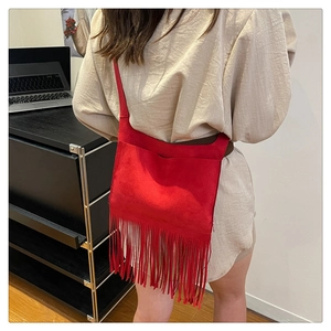 Détail du sac cabas en daim rouge avec de longues franges et une large bandoulière