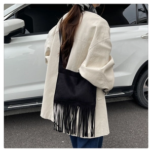 Détail d'un sac bandoulière noir vintage montrant de longues franges et une texture mate