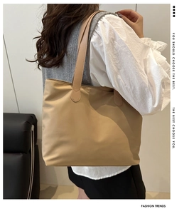 Minimalist beige tote bag shoulder strap detail on model showing high capacity design