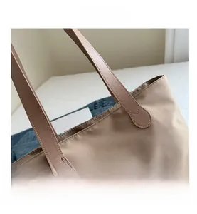 Close-up of khaki tote bag showing reinforced stitching on the durable faux leather handles