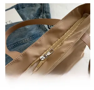 Detail view of khaki tote bag featuring smooth metal zipper and durable synthetic handles