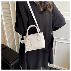 Détail du sac blanc en cuir PU grainé avec pendentif perle et nœud en dentelle