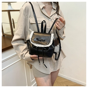 Detail shot of mini black bucket backpack with white lace trim and bow accent