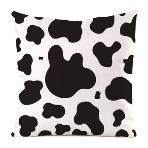 Close-up of black and white cow print pillow cover with faux silk polyester texture
