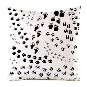 Detailed pattern of black animal footprints printed on a white faux silk cushion cover