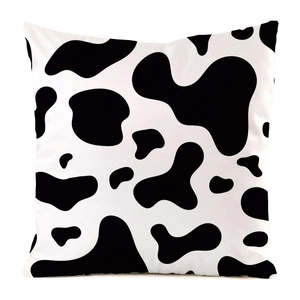 Close-up of square cow print cushion cover with black and white faux silk texture