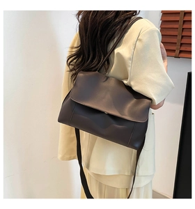 Detail of a dark brown crossbody messenger bag with flap closure on a female model