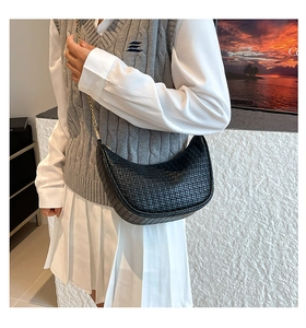 Détail du sac demi-lune noir en similicuir tressé avec chaîne dorée sur un mannequin