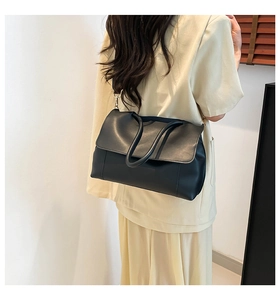 Detail view of large black retro briefcase with soft leather texture and shoulder strap