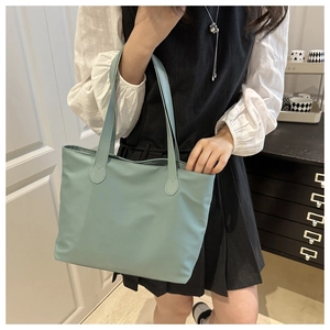 Detail of mint green tote bag showing smooth texture and long shoulder straps for daily use