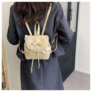 Close-up of beige mini backpack with lace trim, bow detail, and drawstring closure