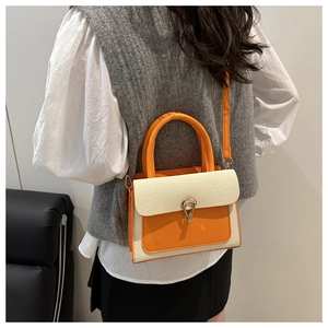 Model wearing orange and beige woven handbag with gold horseshoe buckle and shoulder strap