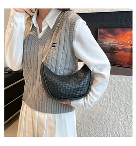Détail du sac croissant tressé noir avec une bandoulière délicate en chaîne dorée chic