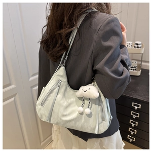 Light green crescent shoulder bag featuring silver zippers and a white plush charm