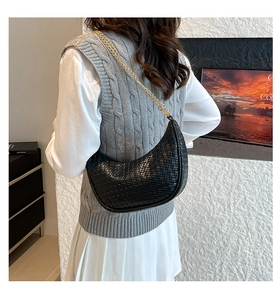 Detail of black woven texture underarm crescent bag with elegant gold chain strap