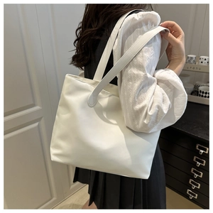 Side view of minimalist white tote bag showing soft fabric texture and shoulder strap detail