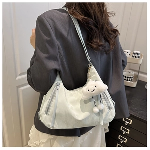 Pale mint crescent tote bag with silver zippers and cloud charm worn by a model