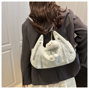 Detail of mint green lightweight backpack featuring a cute plush cloud pendant and zipper