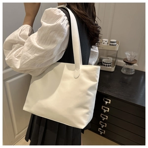 Minimalist white tote bag showing spacious capacity and long shoulder strap in daily use