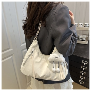 Detail of white PU leather shoulder bag featuring a tassel zipper and plush cloud charm