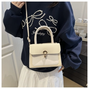 Detail of the chic beige satchel with textured panel and decorative gold horseshoe clasp