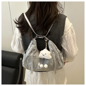 Silver metallic convertible backpack with white plush charm and sleek zipper details