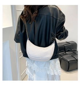 Modèle portant un sac demi-lune blanc tressé avec bandoulière en chaîne dorée
