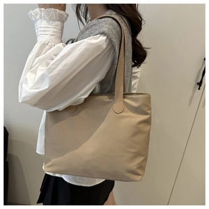 Minimalist beige tote bag styled with a grey vest and white shirt for a chic look