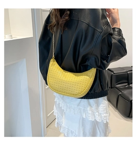 Dettaglio di una borsa a mezzaluna intrecciata giallo acceso con catena d'oro indossata