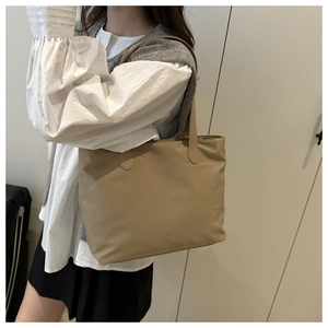 Detail of minimalist beige nylon tote bag showing durable texture and slim shoulder straps