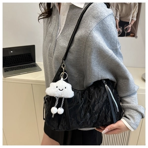Close-up of black pleated tote bag with a white cloud plush charm and metallic zipper