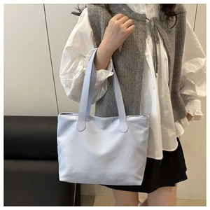 Detailed view of light blue nylon tote bag on shoulder for daily commute style