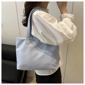 Model wearing a light blue tote bag in a minimalist indoor setting showing size and fit