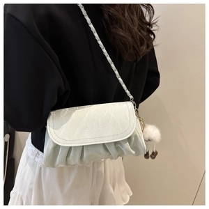 Detail view of white pleated leather crossbody bag with chain strap and plush ball charm