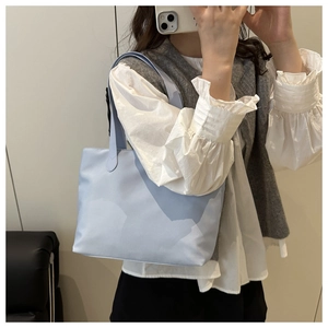 Detail of light blue tote bag featuring deep blue abstract patterns and nylon texture