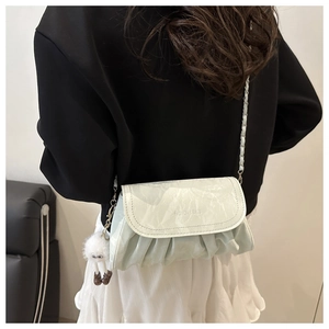 Detail of light green ruched cloud bag with fashion text and white plush charm on model