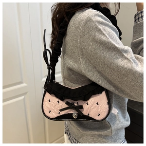 Détail du sac à main à carreaux rose et noir avec volants, nœud et pendentif cœur