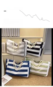 Detail of four striped canvas tote bags in gray, black, blue, and green with rope handles